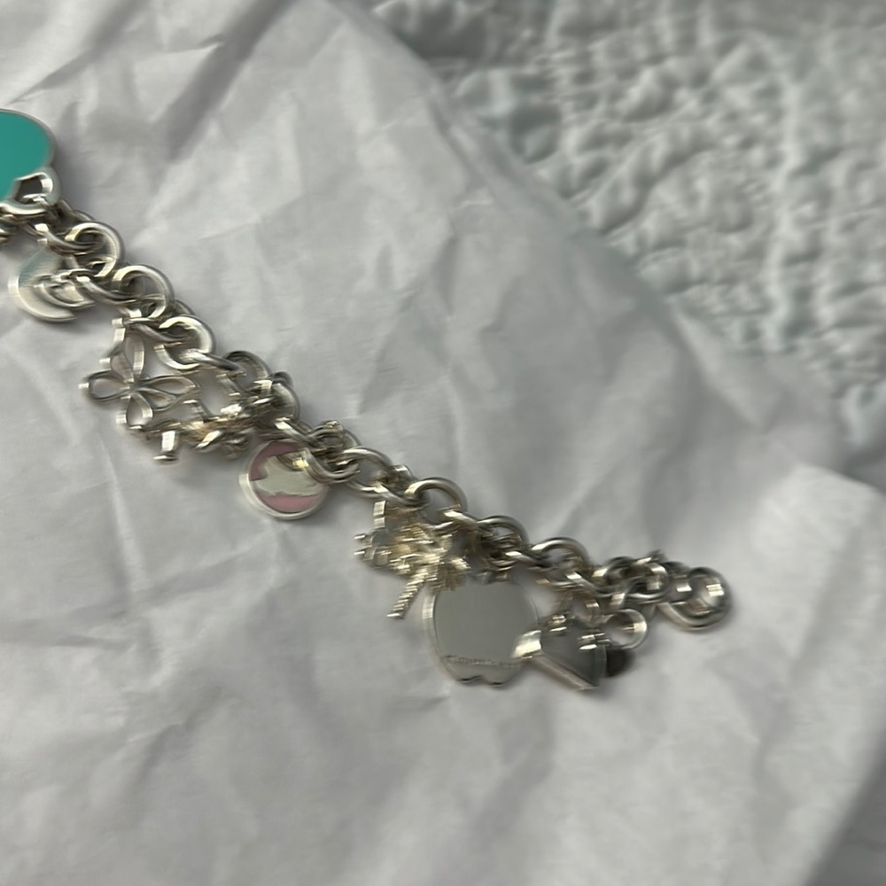 Authentic Tiffany silver charm bracelet. On the rolo heart charm bracelet,